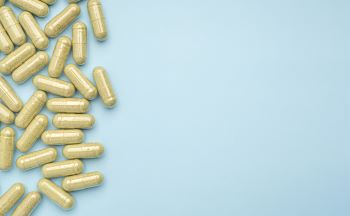 kratom capsules laying out on a blue background