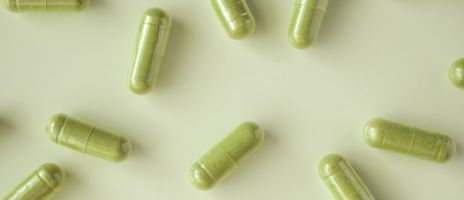 Green vein kratom capsules on a background with a light olive green shade