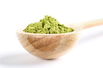 close up of kratom powder in a light wooden spoon