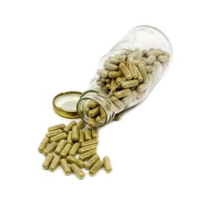 kratom capsules in a glass jar on a white background