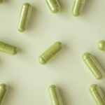 Green Vein capsules laid out on a table with a green hue.