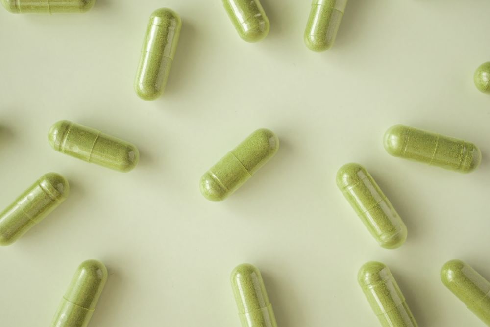 Green Vein capsules laid out on a table with a green hue.