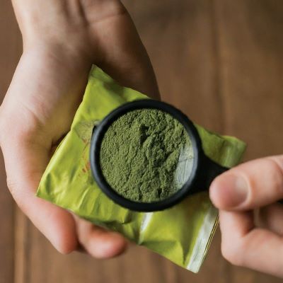 examining kratom powder in bag under magnifying glass