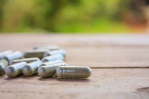 close up of kratom capsules laid out on wooden table