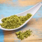 kratom powder on white spoon on colorful wooden table